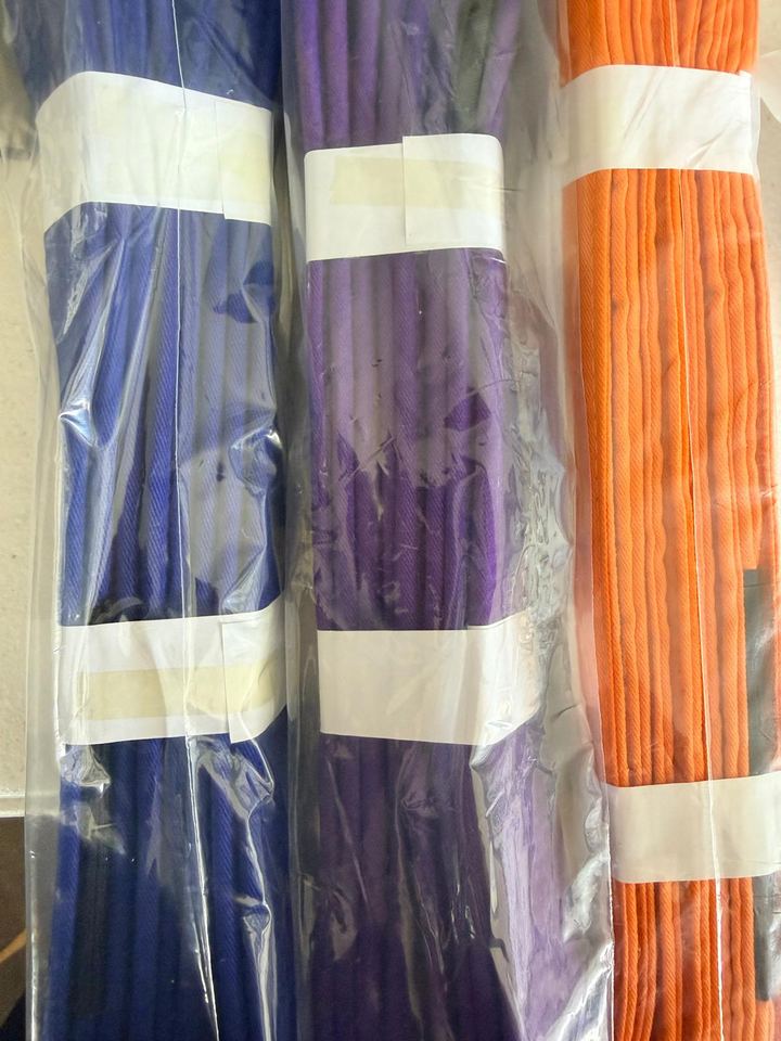Blue, purple and orange cotton BJJ belts, bundled in clear bags