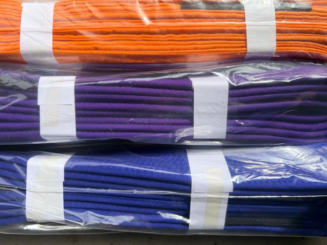 Orange, purple and blue cotton BJJ belts, bundled in clear bags
